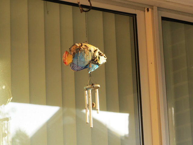 A fish windchime, covered in bird crap.