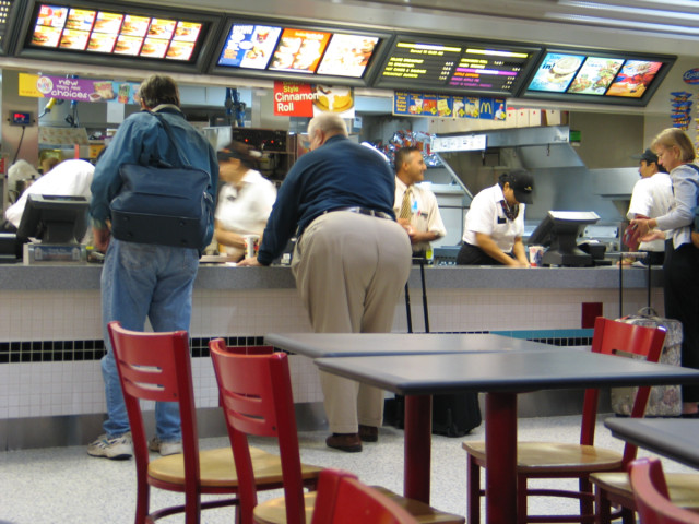 A strangely proportioned gentleman standing at a McDonalds counter.